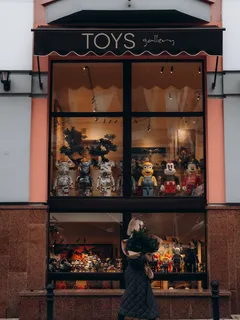 Žena kráčí kolem výlohy s plyšovými hračkami