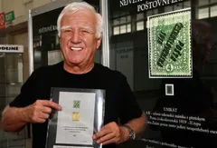 Muž ukazuje vzácnou českou poštovní známku na výstavě filatelie.