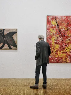Muž stojící před obrazem v galerii umění